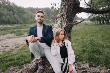 Yakışıklı bir adam ve sarışın bir kız nehir ve ormanın yakınındaki çimlerde yürüyorlar. İnekler ve atlarla otlağın arka planında el ele tutuşup gülümsüyorlar.