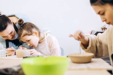 Anne ve kızı çömlek atölyesinde ateş etmeden önce bir tabağı lavanta dallarıyla süslemişler.