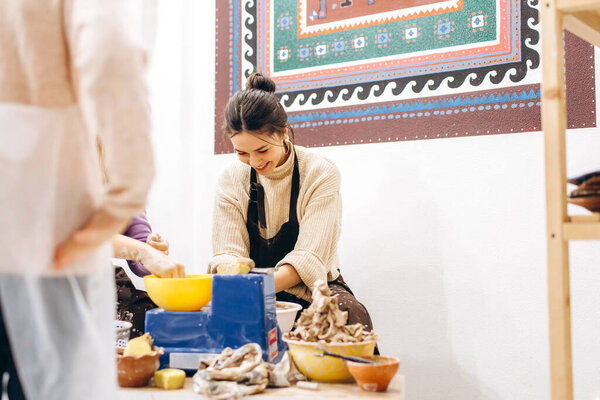 Творческий процесс создания керамики матерью и дочерьми. Руки женщины в мастерской по керамике.