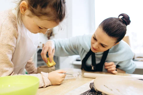 Mother and daughter decorate a clay plate before firing in a pottery studio, decorate a plate with lavender branches