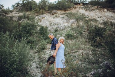 Yaşlı çift doğada dinleniyor ve el ele tutuşuyorlar.