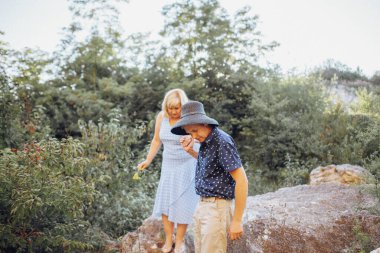 Yaşlı çift doğada dinleniyor ve el ele tutuşuyorlar.