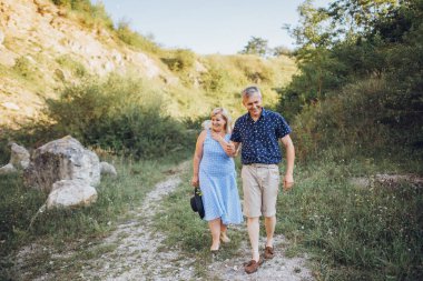 Yaşlı bir çift yazın kayalarla doğada dinleniyor. Çimlerin üzerinde birlikte yürüyoruz