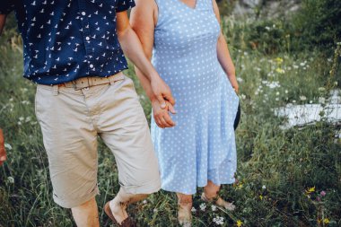 Yaşlı çift doğada dinleniyor ve el ele tutuşuyorlar.