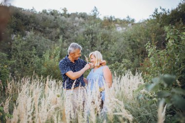 Kayaların arasındaki parkta kucaklaşan mutlu kıdemli adam ve kadın. Kıdemli çift yazın yürüyor ve eğleniyor.