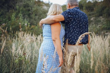 Kayaların arasındaki parkta kucaklaşan mutlu kıdemli adam ve kadın. Kıdemli çift yazın yürüyor ve eğleniyor.