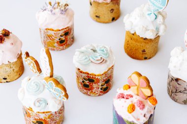 Kurabiye, bize ve çiçeklerle süslenmiş Paskalya pastaları. Beyaz arka planda süslemeleri olan ev yapımı Paskalya pastası.