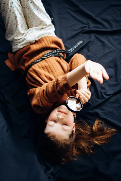 Cute Girl Looks Magnifying Glass While Lying Dark Background — Stock Photo, Image