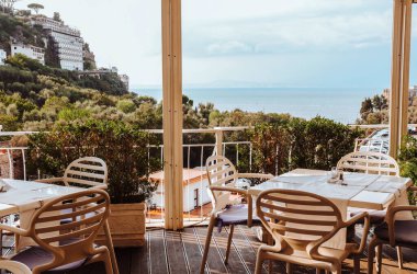 Restoranın terasından güzel bir Sorrento deniz manzarası boş masalar ve şık bej sandalyeler. Sakin yaz deniz manzarası, Sorrento, Güney İtalya, Campania.