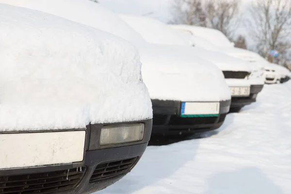 Samochody pokryte śniegiem zaparkowane w rzędzie obok siebie. — Zdjęcie stockowe