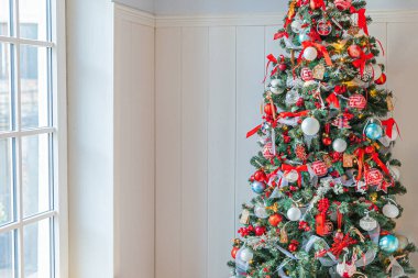 Klasik Noel yılbaşı ağacı kırmızı ve beyaz süsleme oyuncakları ve top ile süslenmiş. Modern klasik stil iç tasarım dairesi. Evde Noel arifesi