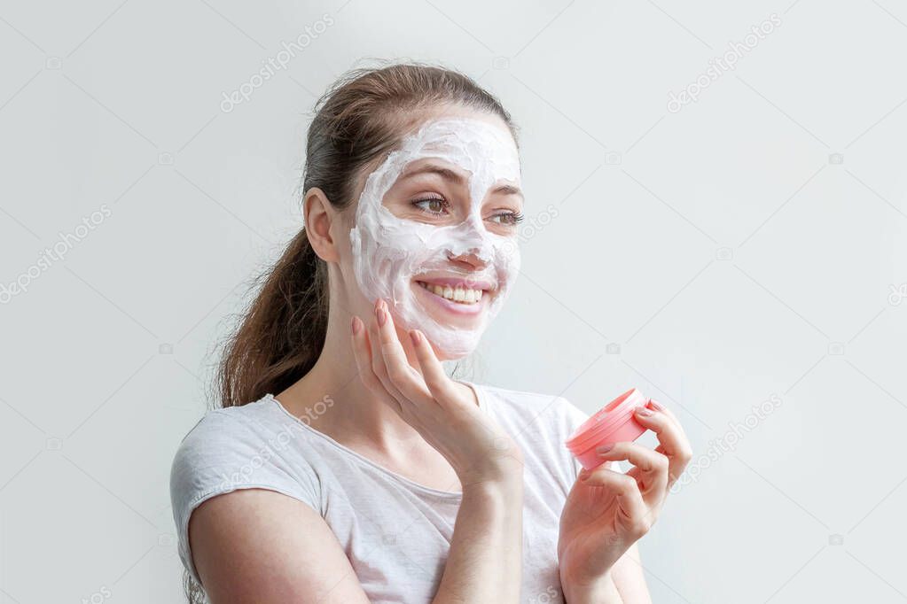 Minimal beauty portrait young woman girl portrait applying white nourishing mask or creme on face isolated on white background. Skincare cleansing eco organic cosmetic spa concept