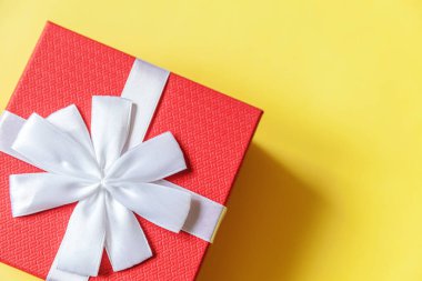 Noel yeni yıl sevgililer günü kutlaması. Romantik bir hediye. Asgari tasarım kırmızı hediye kutusu sarı renkli arka planda izole edilmiş. Düz görünüm kopyalama alanı