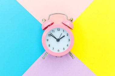Çalan ikiz çan klasik alarm saati mavi pembe renkli renkli geometrik arkaplanda izole edilmiş. Hayatın dinlenme saatleri. İyi sabahlar. Uyanık kalma kavramı. Düz görünüm kopyalama alanı