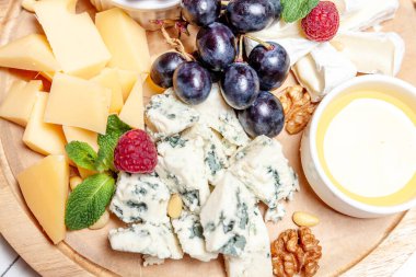 Farklı peynir çeşitleri olan bir pano. Peynirler, peynirli, peynirli, peynirli, peynirli, peynirli, ballı, peynirli, peynirli, peynirli, peynirli ve üzümlü karışımı. Restoran menüsü kahvaltı tabağı. Sağlıklı çerez çeşitleri