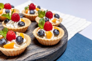 Tahta tepside çeşitli meyveli ve çilekli turtalar. Lezzetli hamur tatlısı turtalar taze ahududu ve peynir kremi ile renklendirilmiş pastalar. Fransız pastanesi.