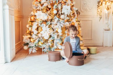 Noel arifesinde Noel ağacının yanında hediye kutusu olan küçük bir kız. Küçük çocuk kış dekorasyonlu, açık renk yatak odasında. Noel Yeni Yıl Kutlama Konsepti Zamanı