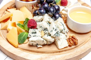 Farklı peynir çeşitleri olan bir pano. Peynirler, peynirli, peynirli, peynirli, peynirli, peynirli, ballı, peynirli, peynirli, peynirli, peynirli ve üzümlü karışımı. Restoran menüsü kahvaltı tabağı. Sağlıklı çerez çeşitleri