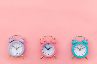 Pembe pastel arka planda izole edilmiş, çalan üç adet klasik alarm saati. Hayatın dinlenme saatleri. İyi sabahlar. Uyanık kalma kavramı. Düz görünüm kopyalama alanı