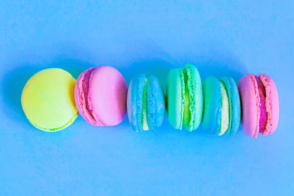 Doce amêndoa rosa colorido azul amarelo macaron verde ou bolo de sobremesa macaroon isolado no fundo pastel azul na moda. Biscoito doce francês. Conceito mínimo de padaria de alimentos. Flat lay vista superior, espaço de cópia — Fotografia de Stock