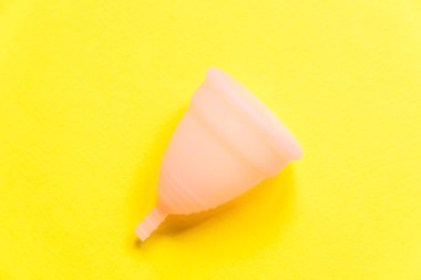 Kısaca, sarı arka planda izole edilmiş en az tasarım pembe menstrüal bardak. Adet döneminde modern kadın alternatif jinekolojik hijyen. Kan için konteynır. Düz görünüm kopyalama alanı