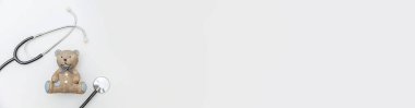 Minimum tasarım oyuncak ayı ve tıbbi ekipman steteskopu beyaz arka planda izole edilmiş. Sağlık hizmetleri çocuk doktoru konsepti. Çocuk doktoru sembolü. Düz konum görünüm kopyalama alanı afişi