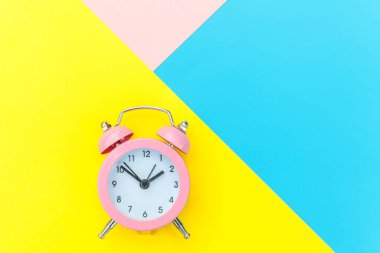Çalan ikiz çan klasik alarm saati mavi pembe renkli renkli geometrik arkaplanda izole edilmiş. Hayatın dinlenme saatleri. İyi sabahlar. Uyanık kalma kavramı. Düz görünüm kopyalama alanı