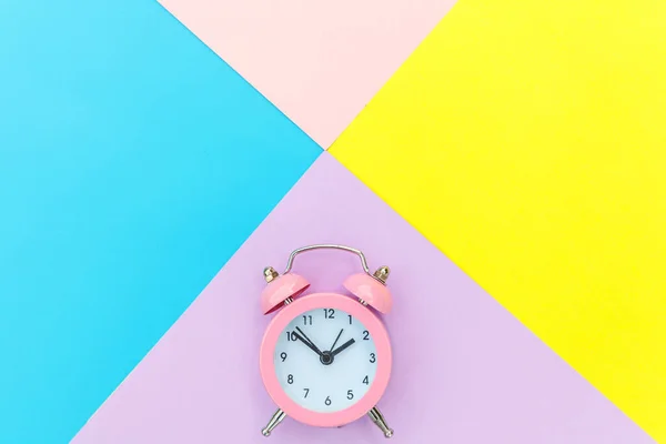 노란색의 연분홍색 파스텔의 기하학적 배경에서 쌍둥이 전형적 시계가 울려퍼진다 아침의 — 스톡 사진