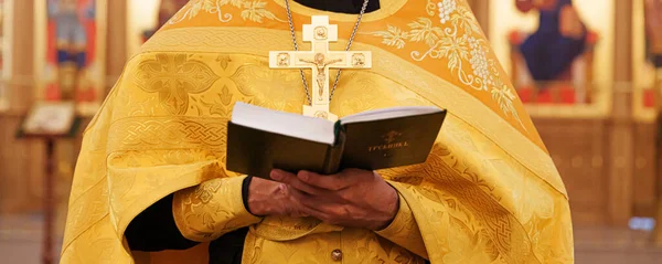 Orthodox Church. Christianity. Priest hands holding Holy Bible book in traditional Orthodox Church background on wedding day Easter Eve or Christmas celebration. Religion faith pray symbol