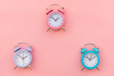 Pembe pastel arka planda izole edilmiş, çalan üç adet klasik alarm saati. Hayatın dinlenme saatleri. İyi sabahlar. Uyanık kalma kavramı. Düz görünüm kopyalama alanı