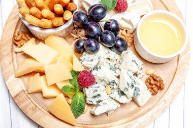 Farklı peynir çeşitleri olan bir pano. Peynirler, peynirli, peynirli, peynirli, peynirli, peynirli, ballı, peynirli, peynirli, peynirli, peynirli ve üzümlü karışımı. Restoran menüsü kahvaltı tabağı. Sağlıklı çerez çeşitleri