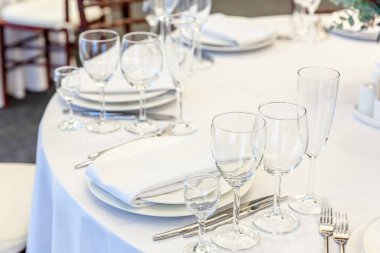 Restoranda peçete bardaklarıyla yemek masası, lüks bir iç mekan. Şık bir düğün ziyafeti dekorasyonu ve yemek servisi tarafından beyaz masa örtüsü üzerinde hazırlanmış yiyecekler.