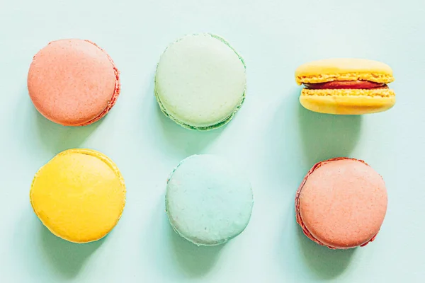 Sweet almond colorful pink blue yellow green macaron or macaroon dessert cake isolated on trendy blue pastel background. French sweet cookie. Minimal food bakery concept. Flat lay top view copy space