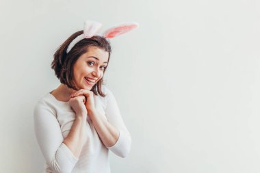 Mutlu Paskalya bayramı bahar kutlamaları. Beyaz arka planda izole edilmiş tavşan kulağı takan genç bir kadın. Tatil için hazırlık. Mutlu ve heyecanlı görünen bir kız, Paskalya gününde eğleniyor.