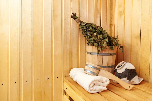 Interior details Finnish sauna steam room with traditional sauna accessories basin birch broom scoop felt hat towel. Traditional old Russian bathhouse SPA Concept. Relax country village bath concept