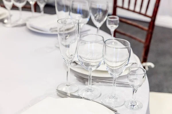 Fancy table set for dinner with napkin glasses in restaurant, luxury interior background. Wedding elegant banquet decoration and items for food arranged by catering service on white tablecloth table