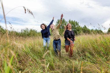 Yaz tatili mutlu insanlar konsepti. Üç arkadaş grubu erkek ve iki kız dışarıda koşup eğleniyorlar. Arkadaşlarla pikniğe gidiyoruz.