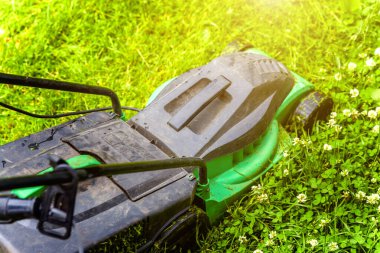 Bahçede çim biçme makinesiyle çim biçen bir adam. Bahçe işleri kırsal yaşam tarzı. Güneş ışığında taze yeşil çimlerin manzarası baharda ya da yaz mevsiminde bahçe manzarası