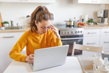 Mobil Ofis evde. Yorgun ve yorgun bir kadın dizüstü bilgisayarda çalışıyor. El ele tutuşup evde mutfakta oturuyor. İçeride çalışan ya da ders çalışan genç bir kız. Serbest ticaret karantina kavramı