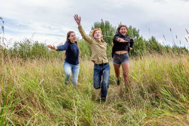 Yaz tatili mutlu insanlar konsepti. Üç arkadaş grubu erkek ve iki kız dışarıda koşup eğleniyorlar. Arkadaşlarla pikniğe gidiyoruz.