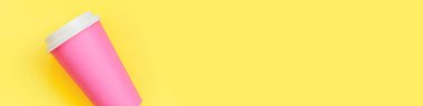Düz dizayn edilmiş pembe kağıt kahve fincanı sarı renkli arka planda izole edilmiş. Paket içecek konteynırı. Günaydın uyanık kavramı. İçkinin şablonu. Üst görünüm kopyalama alanı afişi