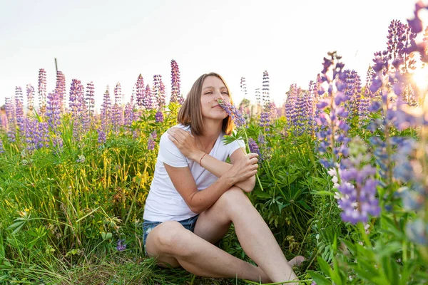 Šťastná dívka se usmívá venku. Krásná mladá brunete žena odpočívající na letním poli s kvetoucími divokými květy zelené pozadí. Svobodná šťastná Evropanka. Pozitivní lidské emoce výraz obličeje. — Stock fotografie