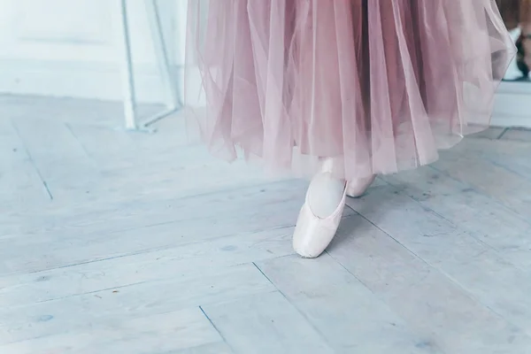 ピンクのチュチュスカートの中のバレリーナの手は 白い光のホールで足の上に点の靴を置きます 若いですクラシックバレエダンサー女の子でダンスクラス — ストック写真