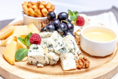 Farklı peynir çeşitleri olan bir pano. Peynirler, peynirli, peynirli, peynirli, peynirli, peynirli, ballı, peynirli, peynirli, peynirli, peynirli ve üzümlü karışımı. Restoran menüsü kahvaltı tabağı. Sağlıklı çerez çeşitleri