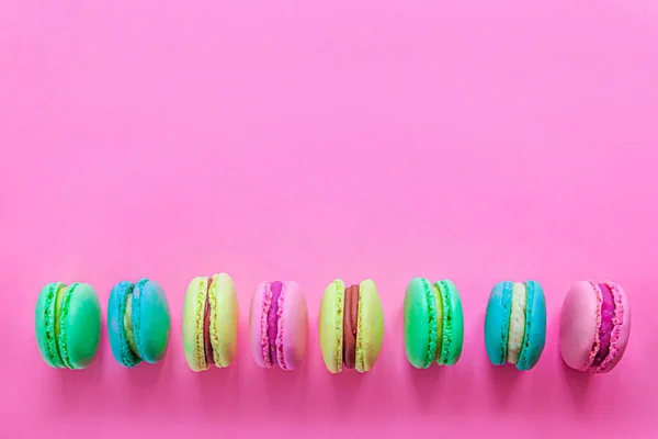 Sweet almond colorful pink blue yellow green macaron or macaroon dessert cake isolated on trendy pink pastel background. French sweet cookie. Minimal food bakery concept. Flat lay top view copy space