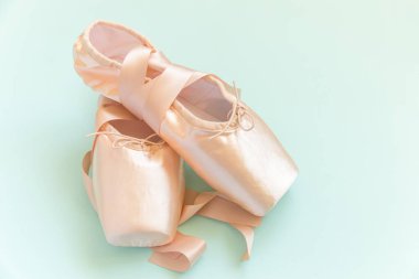 Mavi arka planda saten kurdeleli yeni pastel bej bale ayakkabıları. Dans eğitimi için klasik balerin ayakkabıları. Bale okulu konsepti. Üst görünüm düz kopya alanı
