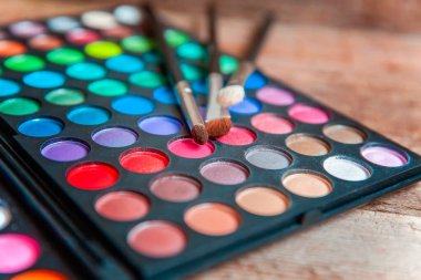 Makyaj ve kozmetik aletleri. Göz farı paletinin farklı tonları ve eski kırsal ahşap arka planda makyaj fırçası. Üst görünüm düz yatay ve resim gibi