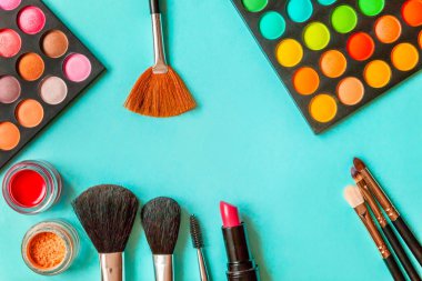 Makyaj ve kozmetik için farklı göz falı tonları ve renkli mavi pastel arka planda makyaj fırçası. Üst görünüm düz yatay ve resim gibi