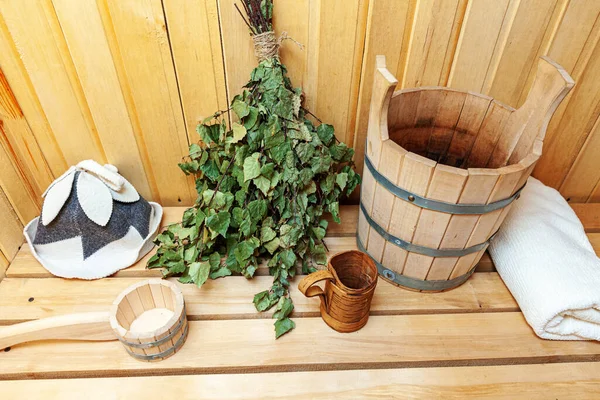 Interior details Finnish sauna steam room with traditional sauna accessories basin birch broom scoop felt hat towel. Traditional old Russian bathhouse SPA Concept. Relax country village bath concept