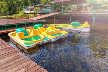 Pedal tekneleri ya da sandallar katamaran istasyonu. Sarı su bisikletleri güneşli yaz gününde marina rıhtımında kilitli. Açık havada yaz tatili aktivitesi